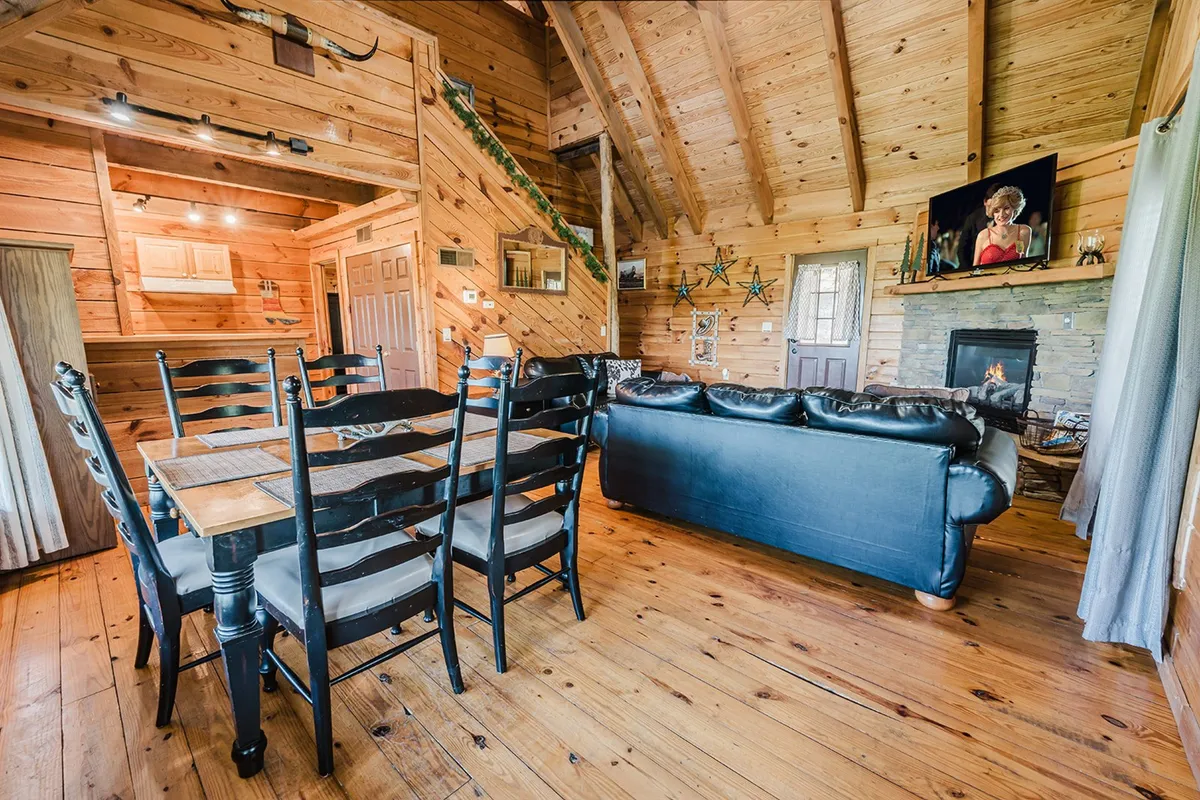 A warm and welcoming multi-use space with a dining table, sofa, fireplace, and staircase. The environment radiates togetherness, comfort, and home-like convenience, perfect for family meals, relaxation, or waiting for quick maintenance support if needed.